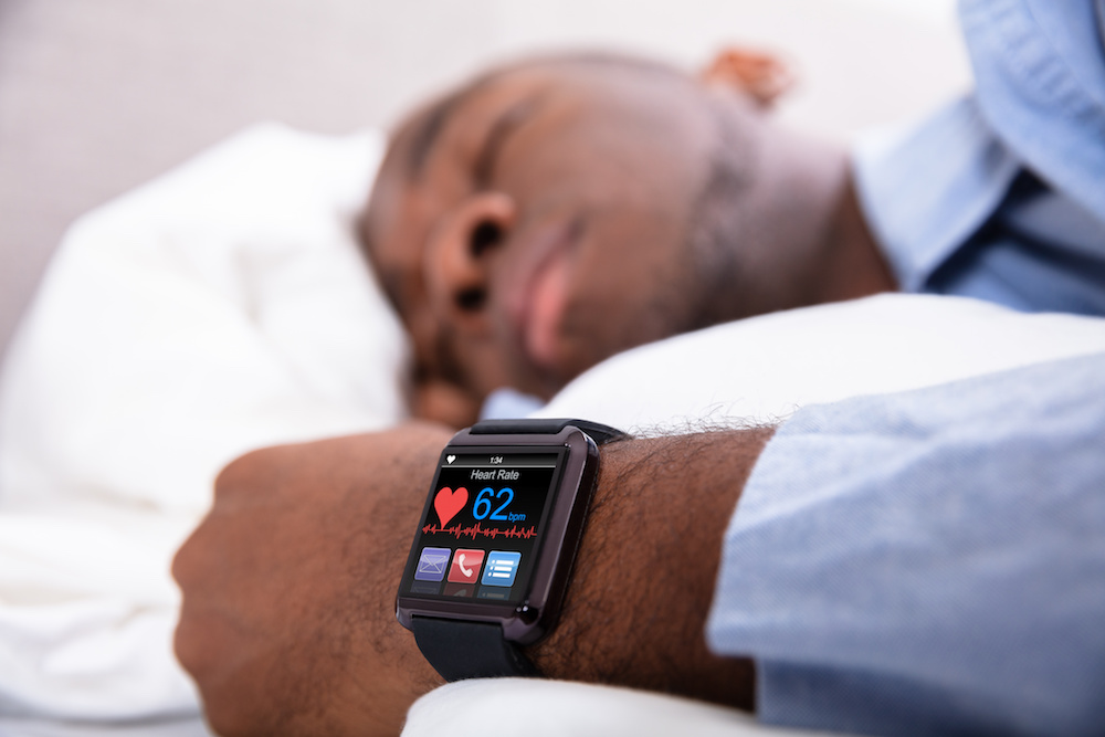 Man sleeping with medical alert smartwatch wearable technology because he has heart problems and it needs to be monitored